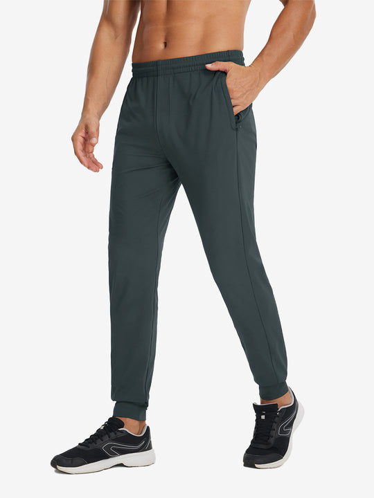 Side view of model with hand in pocket wearing lightweight traning track pants in dark grey.