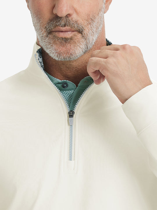 Close-up from nose to chest, showing collar and zipper detail of the cream golf pullover.