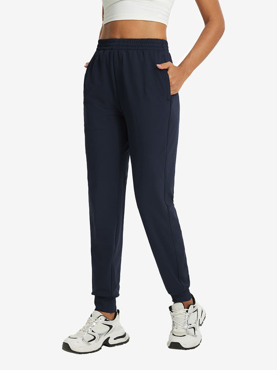 Model with hand in pocket wearing lightweight women's stretchy joggers sweatpants in navy.