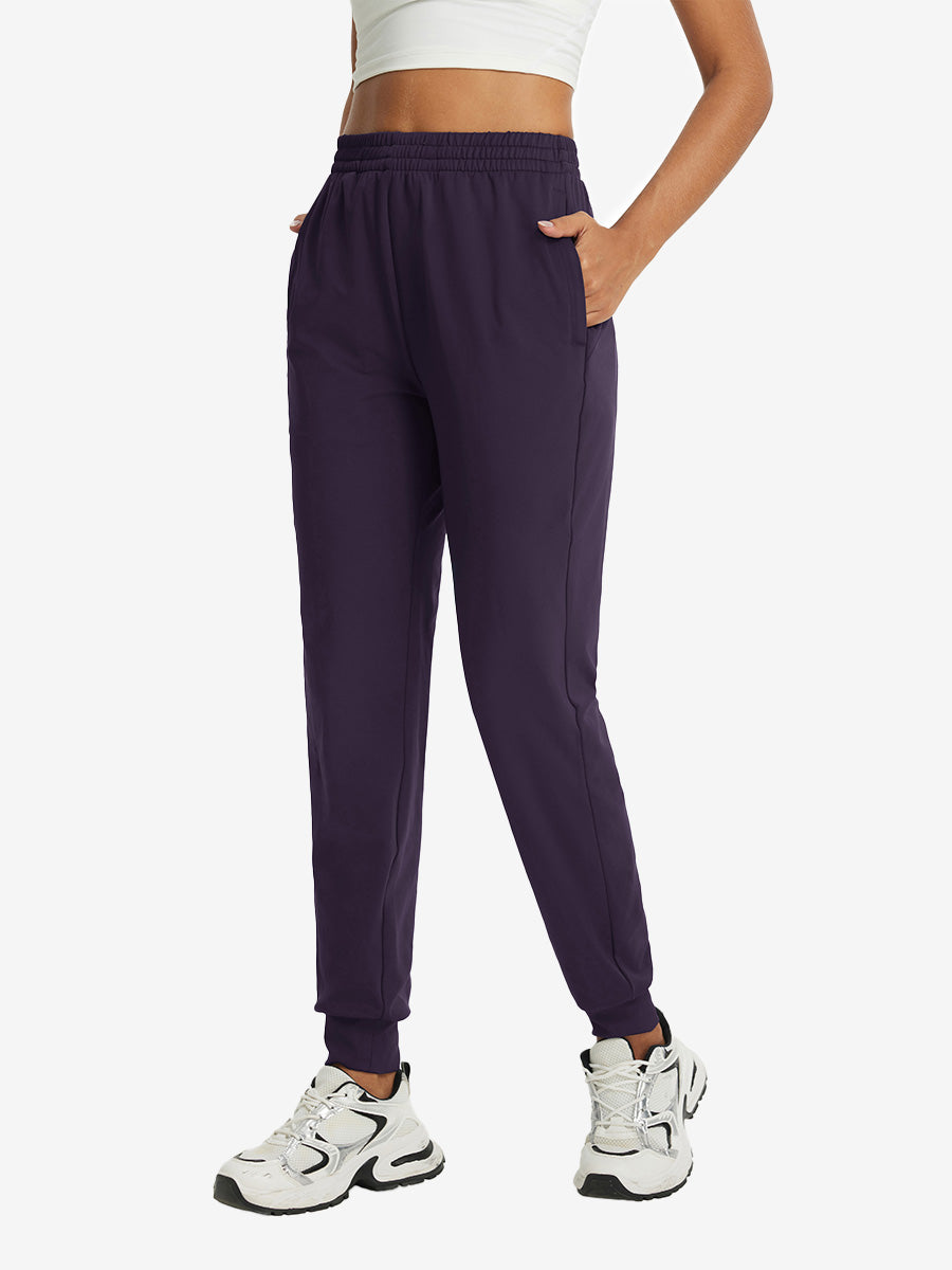 Model with hand in pocket wearing lightweight women's stretchy joggers sweatpants in dark purple.