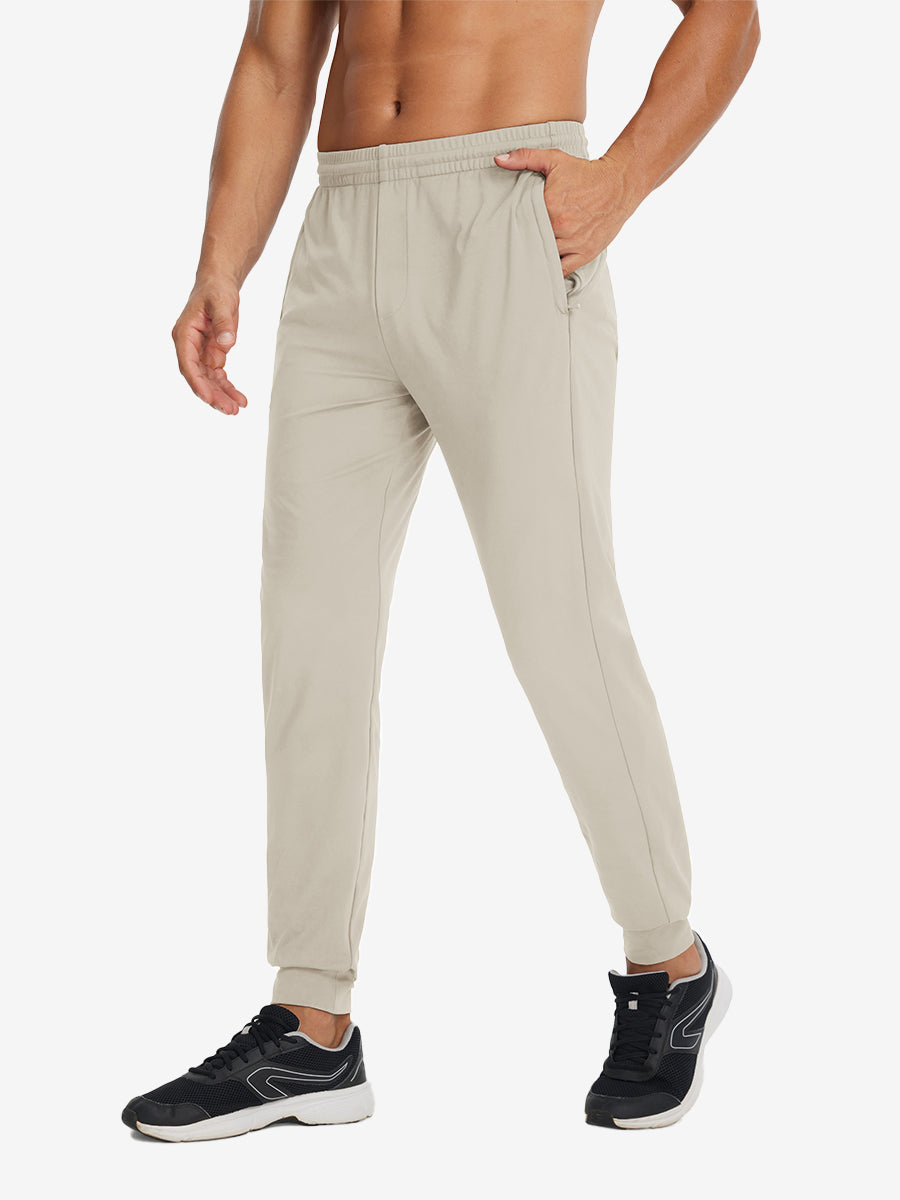 Side view of model with hand in pocket wearing lightweight traning track pants in khaki.