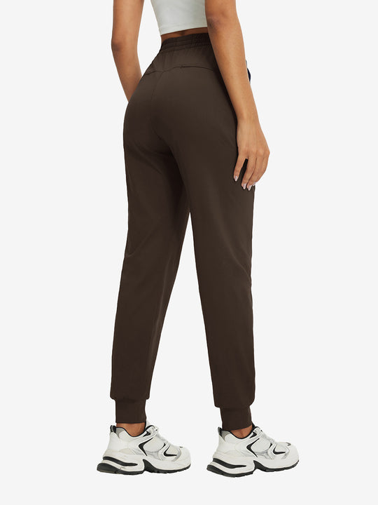 Back view of lightweight women's stretchy joggers sweatpants on model, shown in coffee brown.