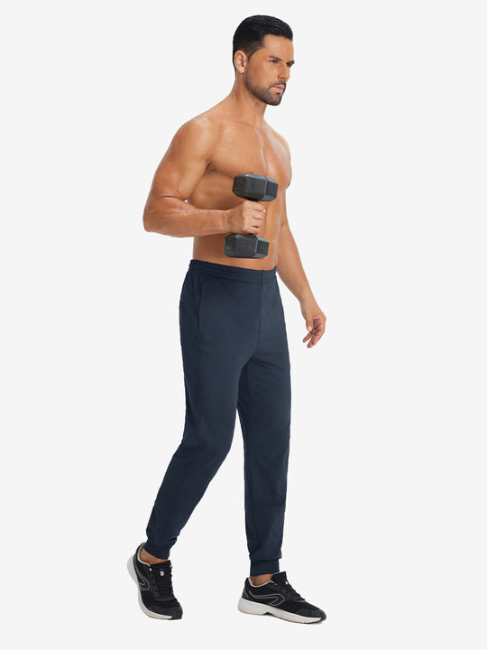 Model holding tennis racket wearing lightweight traning track pants in navy.