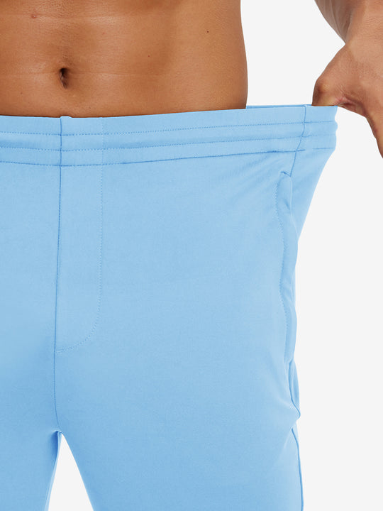 Model stretching waistband to show fit of lightweight traning track pants in light blue.